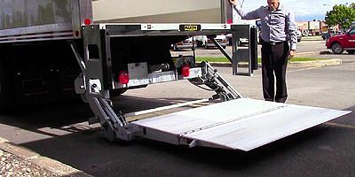 A man standing next to a California trucking truck with a ramp.