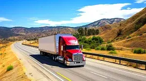 A red semi truck driving down a highway while crossing state lines.